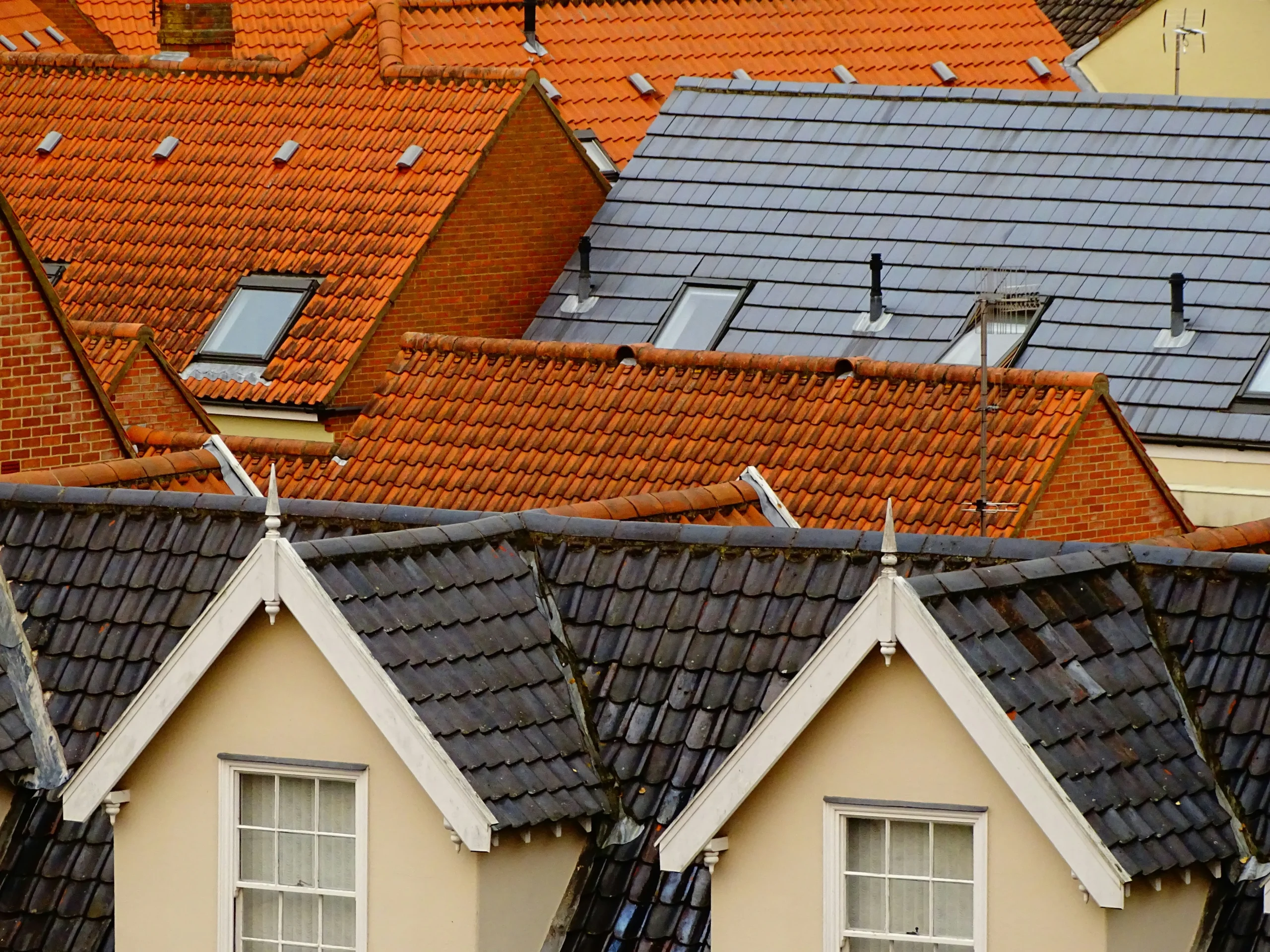 Close-up view of various tiled rooftops with red clay and grey slate tiles on residential houses in Redditch.